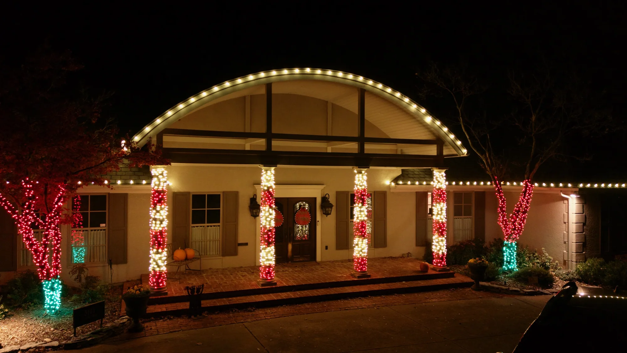 Portico columns wrapped in red and white. Christmas Lighting by LIT Outdoor Lighting in Tulsa.