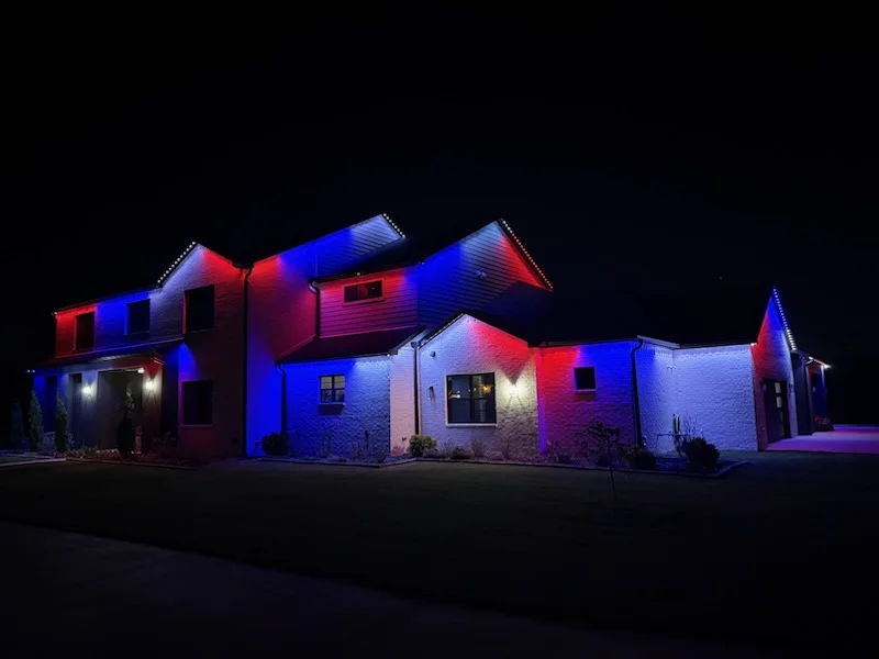 Stone home roofline in red and blue. Permanent Lighting by LIT Outdoor Lighting in Tulsa.