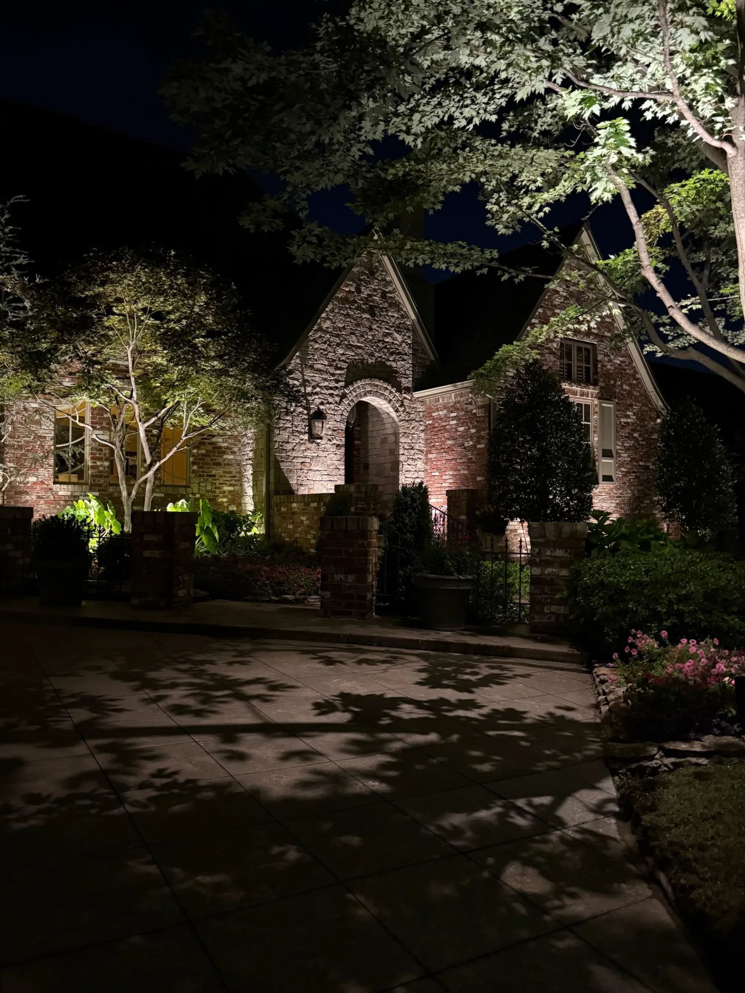 Stone cottage and trees lit along the drive. Landscape Lighting by LIT Outdoor Lighting in Tulsa.