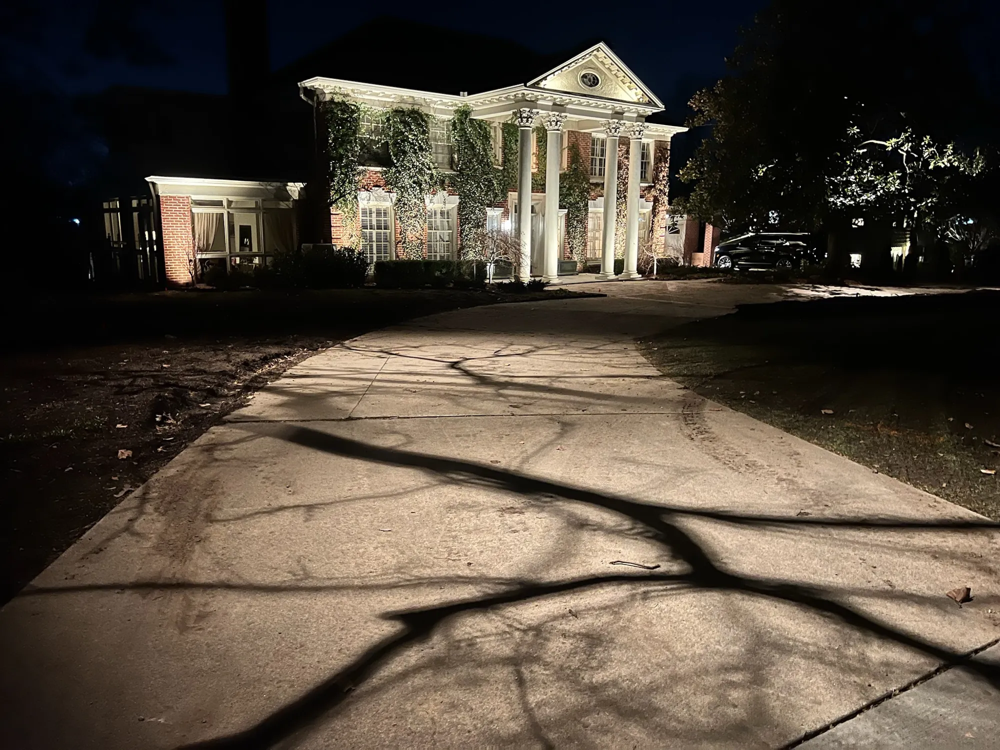 Columned house lit up a long drive. Landscape Lighting by LIT Outdoor Lighting in Tulsa.