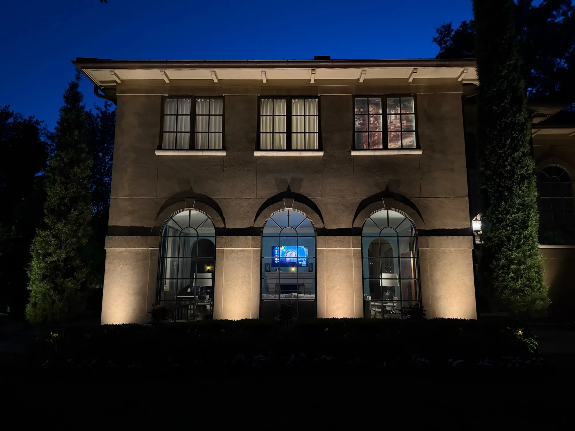 Arched windows and plaster facade washed in light. Landscape Lighting by LIT Outdoor Lighting in Tulsa.