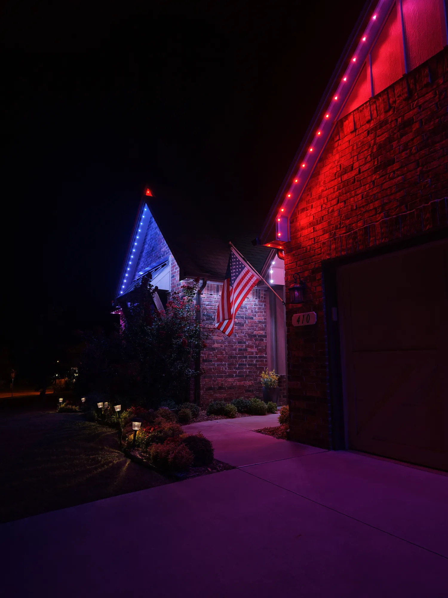 Red roofline beside a blue gable. Permanent Lighting by LIT Outdoor Lighting in Tulsa.