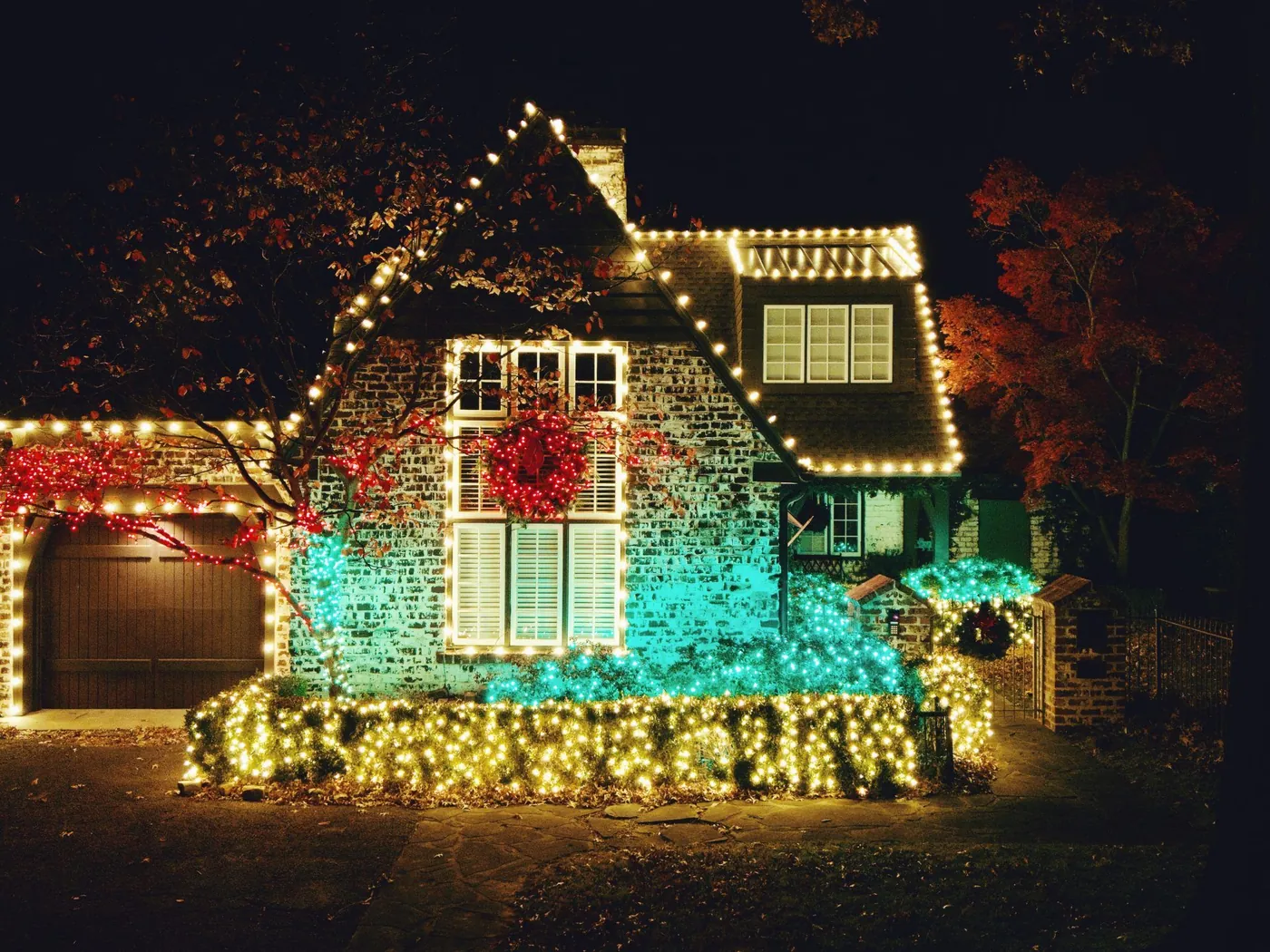 A Tudor home lit in teal and warm white Christmas lighting